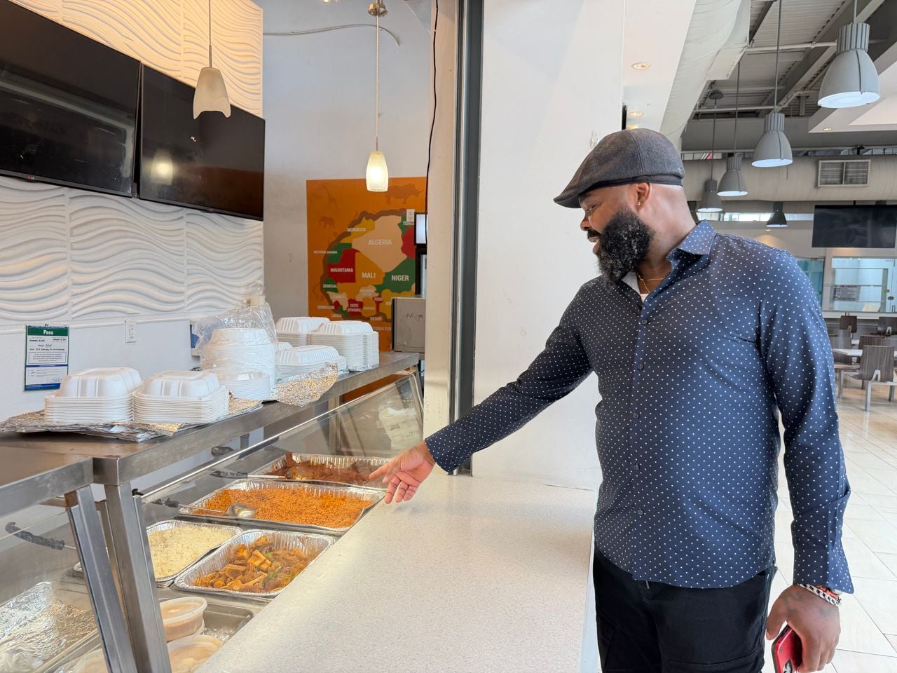 Chef James Obazee points at the dishes displayed at Naija Jollof