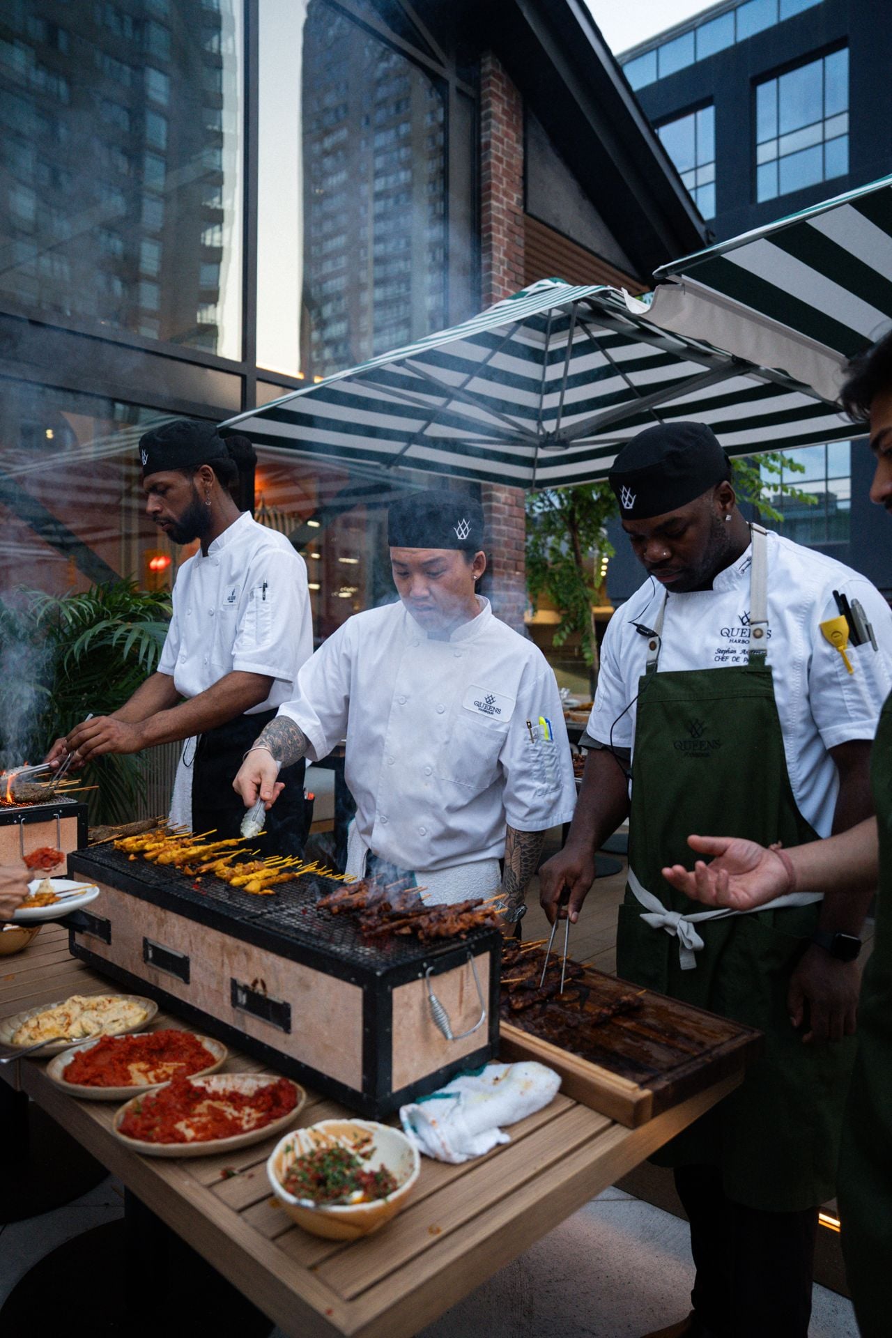 Chefs grill skewers on the patio at Queens Harbour
