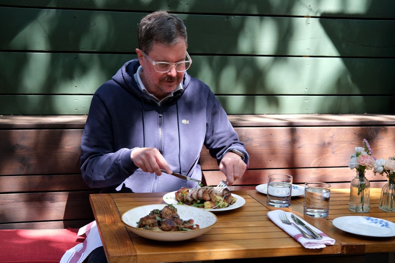 Lucas McCann sits at a table and eats a pork chop