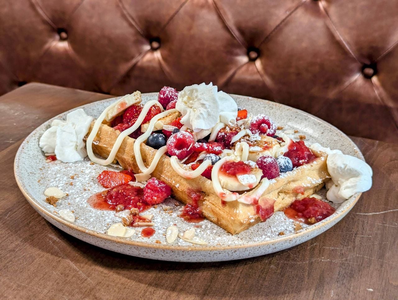 Waffles topped with berries, bananas and whipped cream