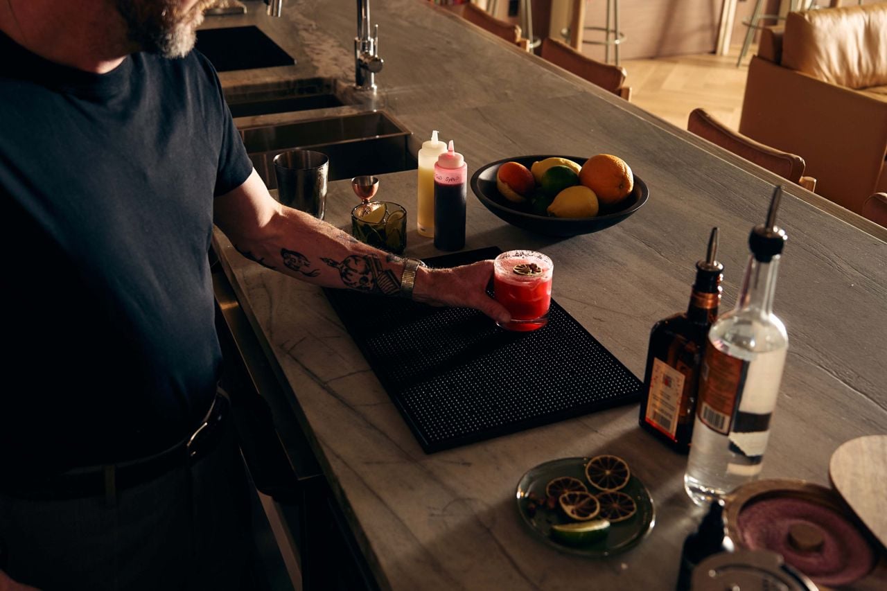 A bartender places a cocktail on the bar