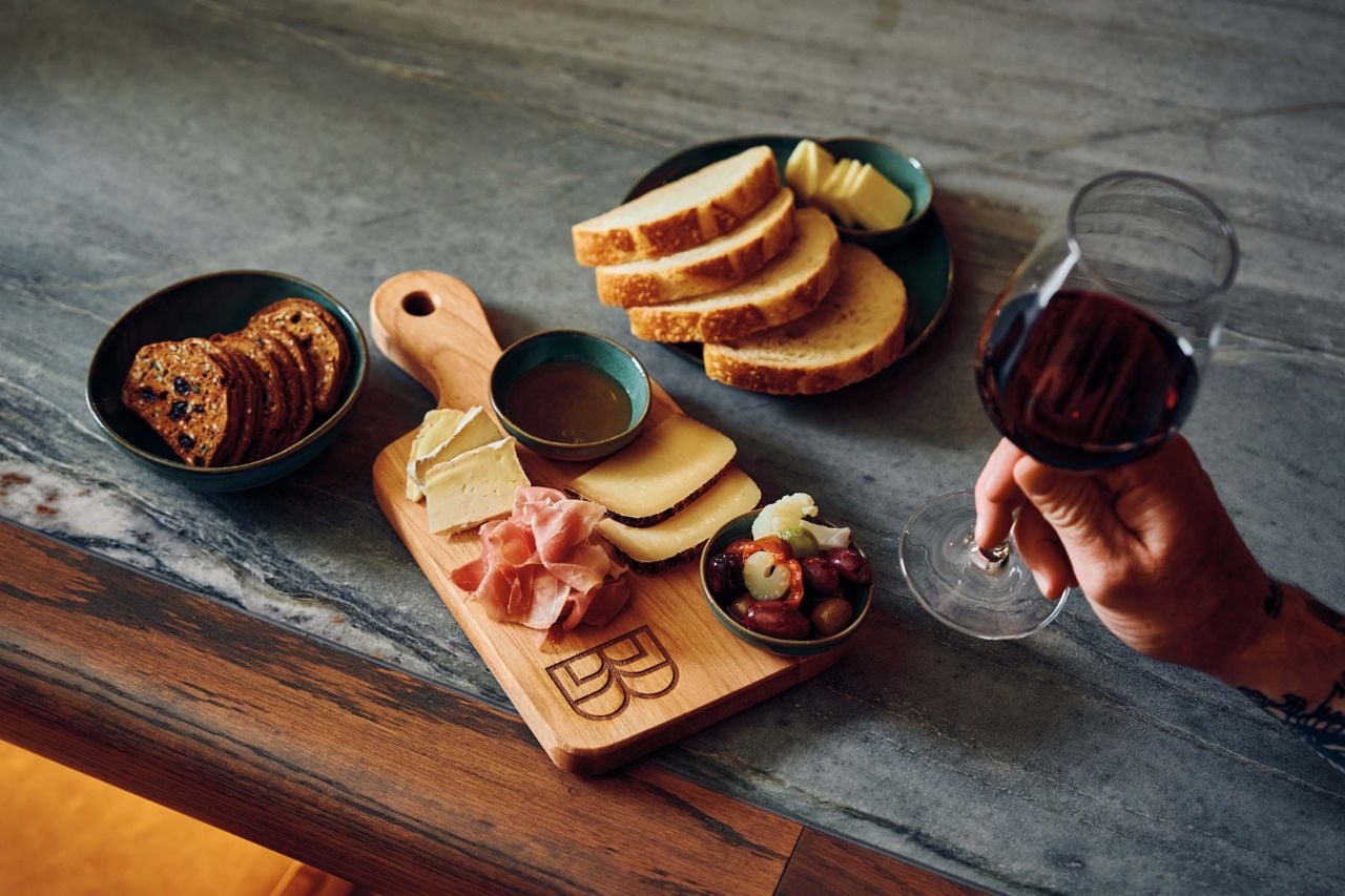 A charcuterie board, bread, crackers and a glass of wine