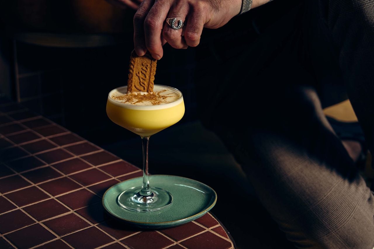 A person dips a cookie in a cocktail