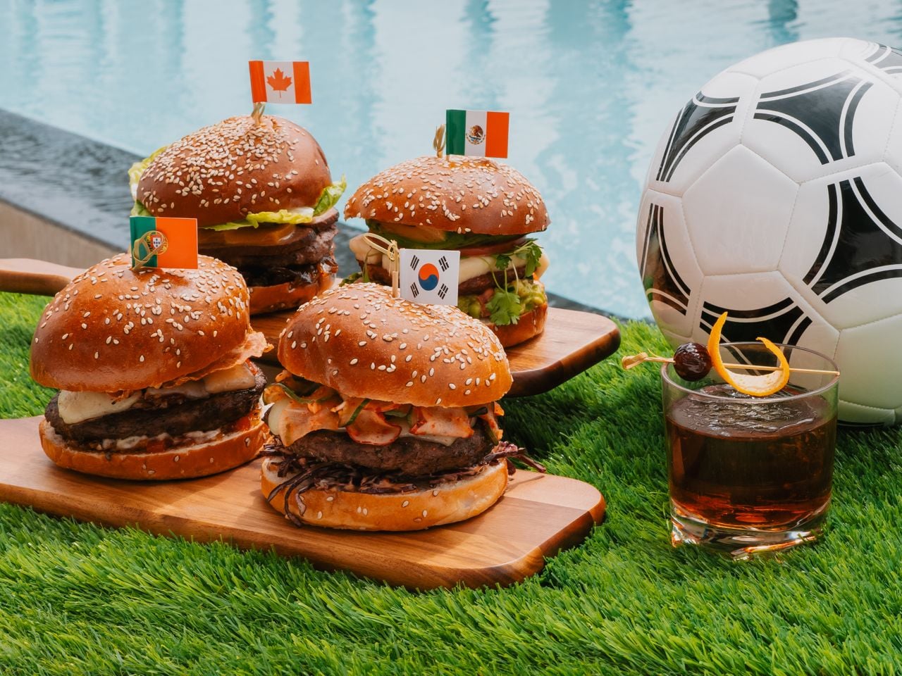 A selection of hamburgers next to a cocktail and a soccer ball