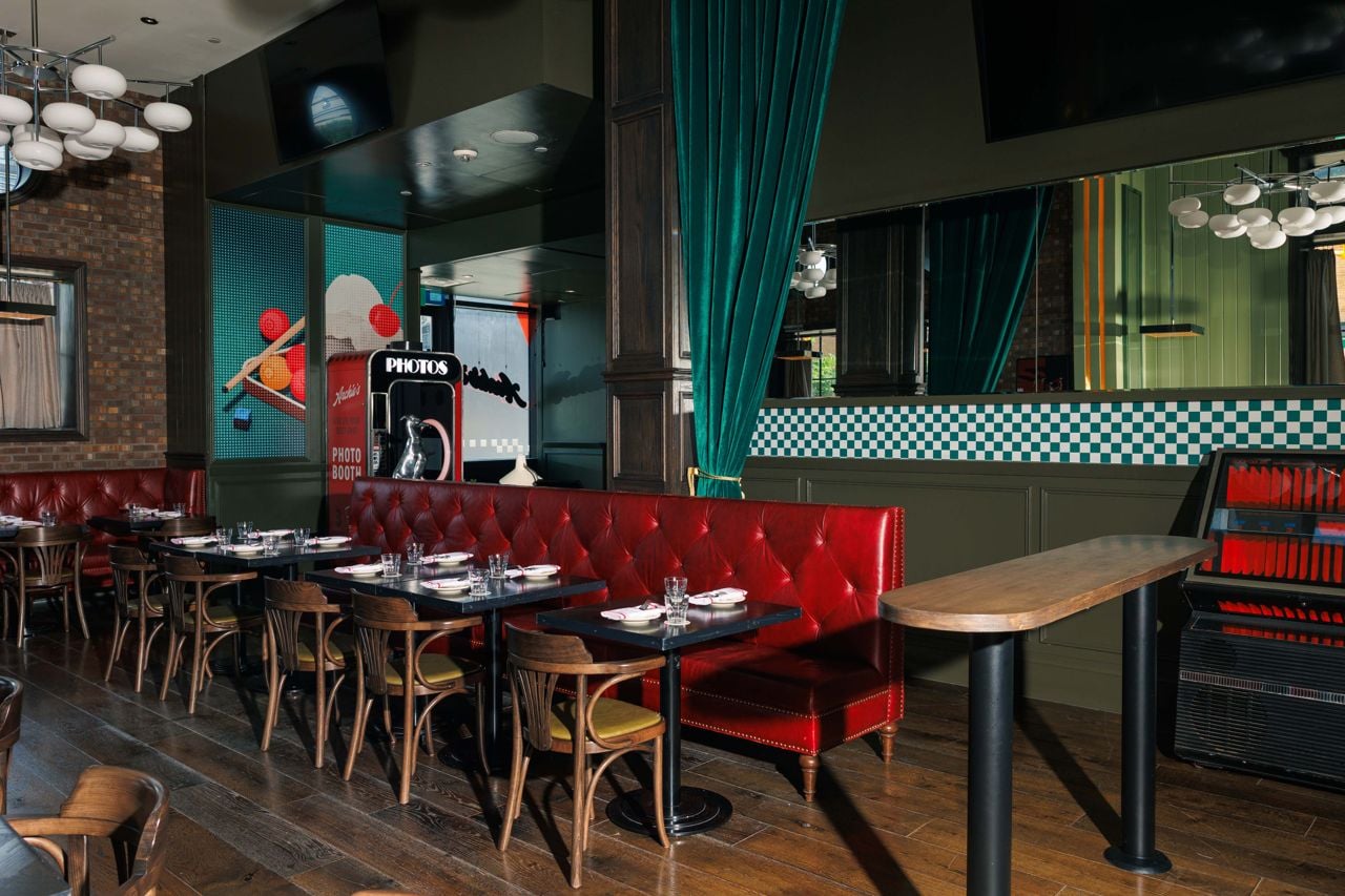 Two-top tables and a photo booth inside Archie's