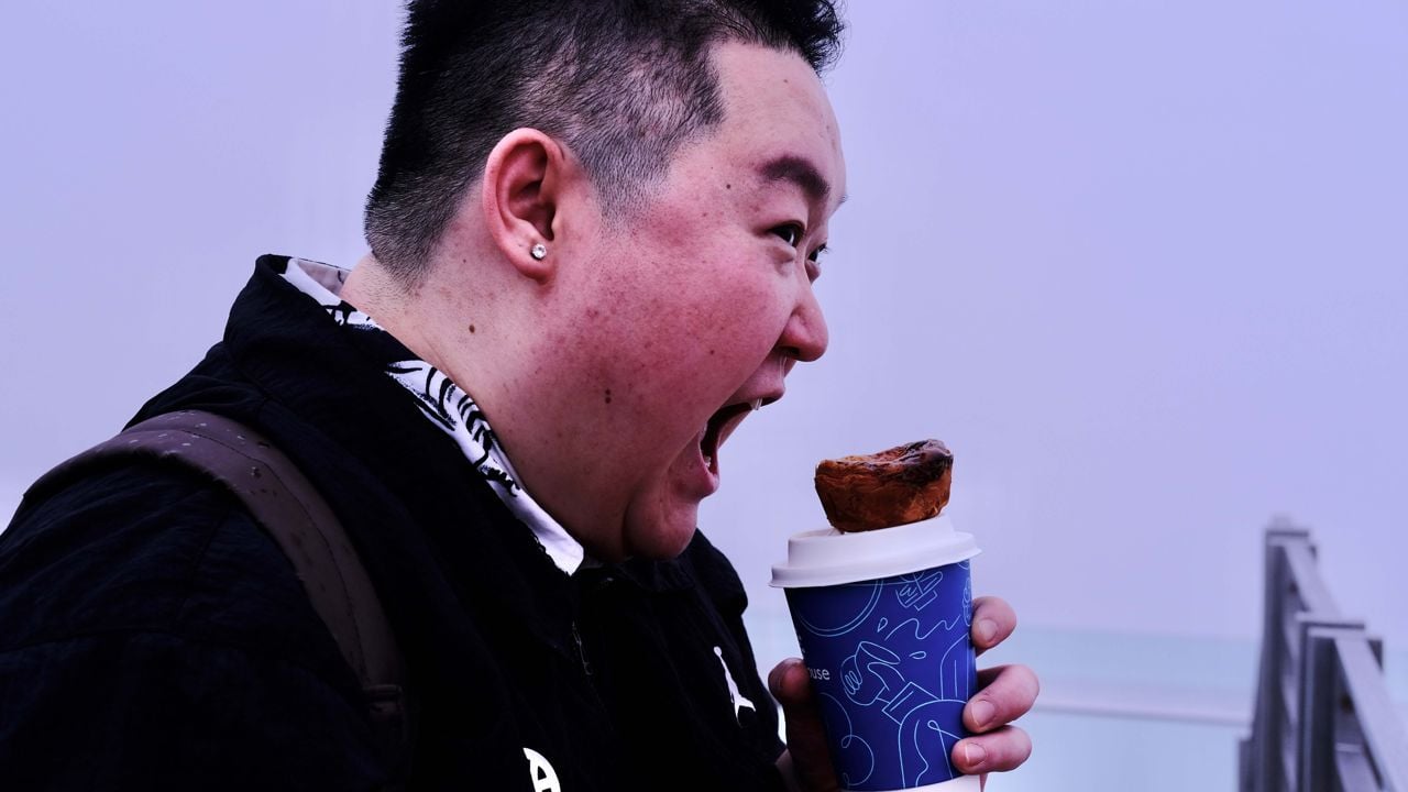 Chef Eva Chin pretends to eat an egg tart, which is balanced on a coffee cup