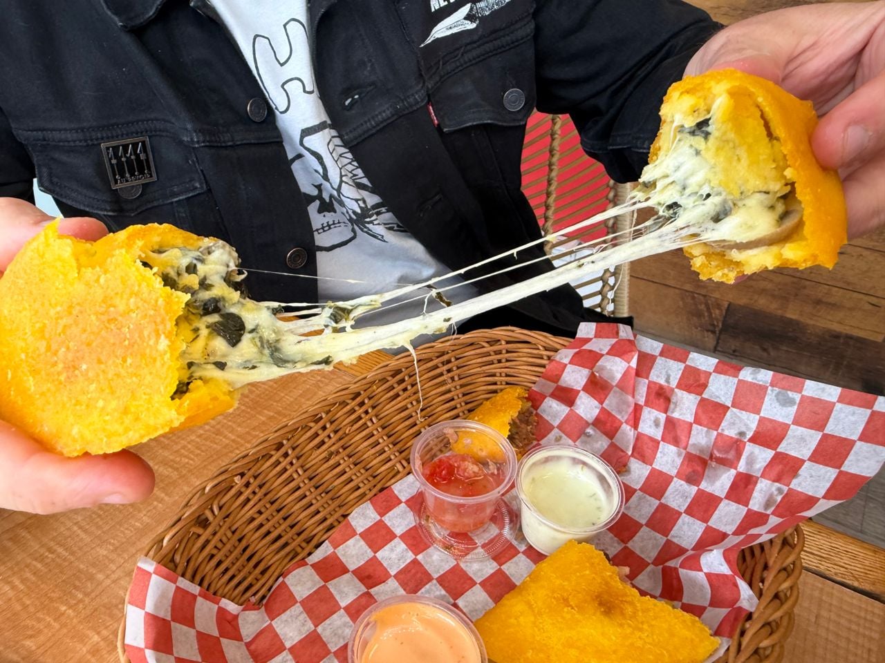 A person pulls apart a cheese and spinach empanada