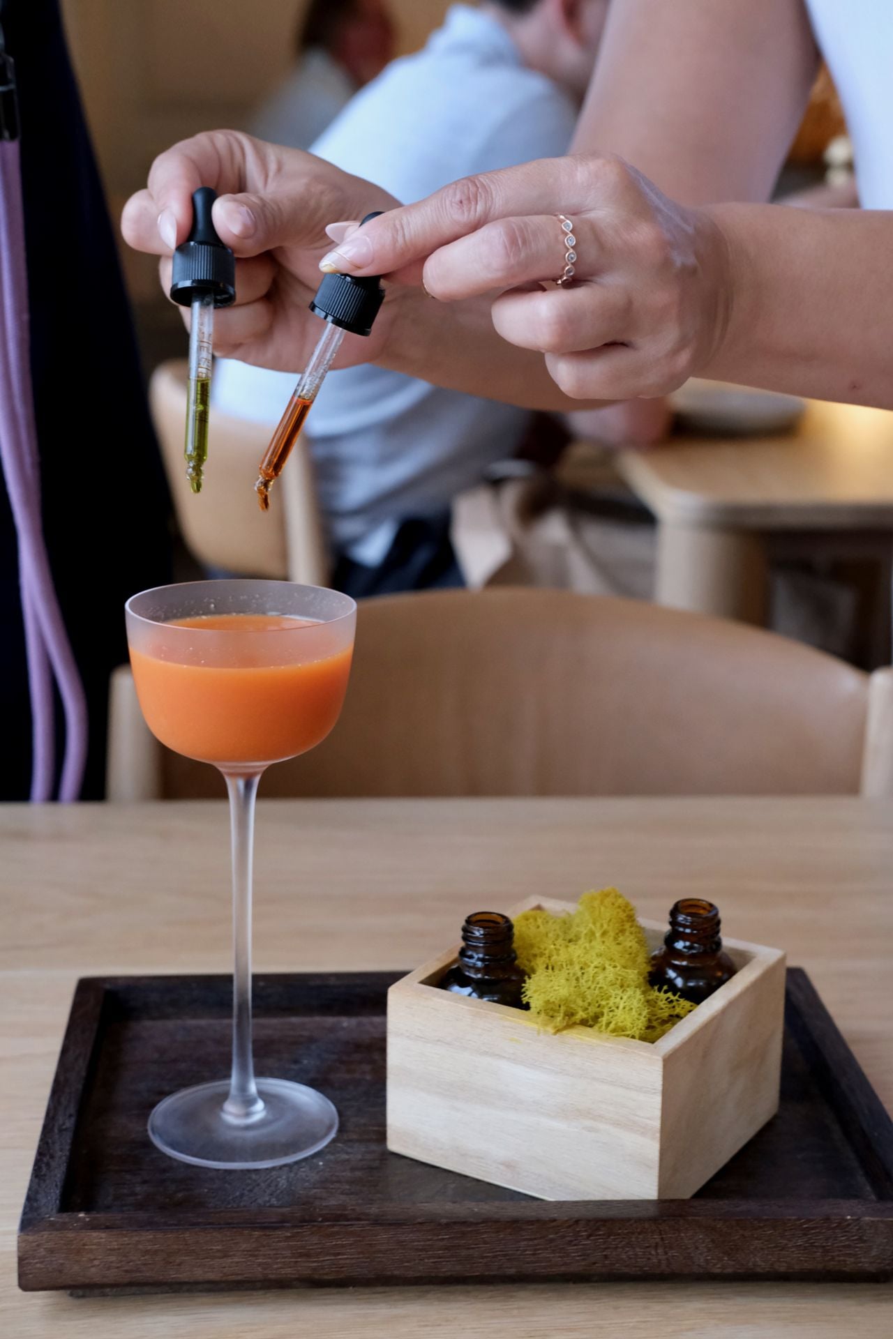 A person adds tincture from droppers into a cocktail