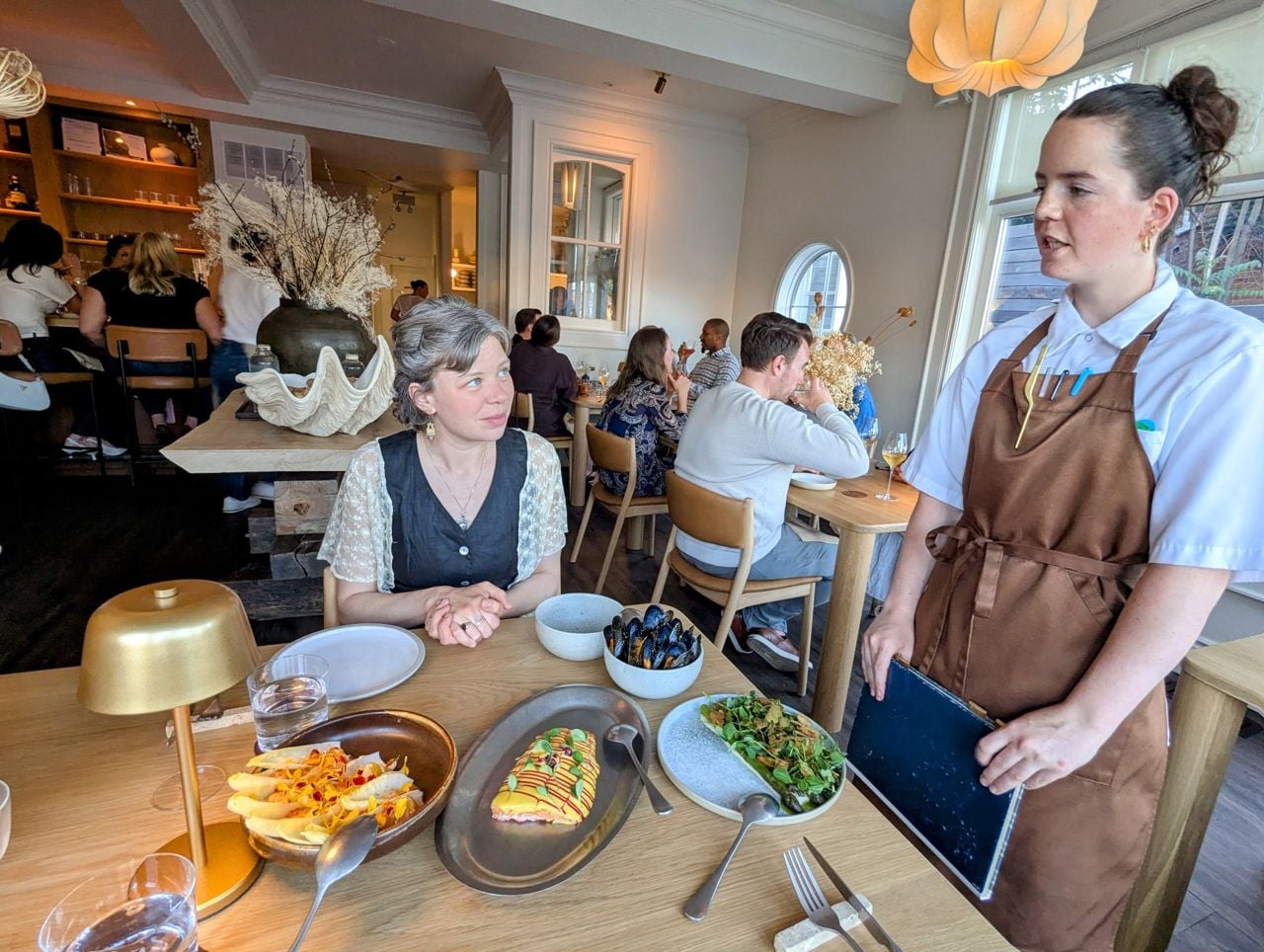 A server at Lore Restaurant explains dishes to a diner