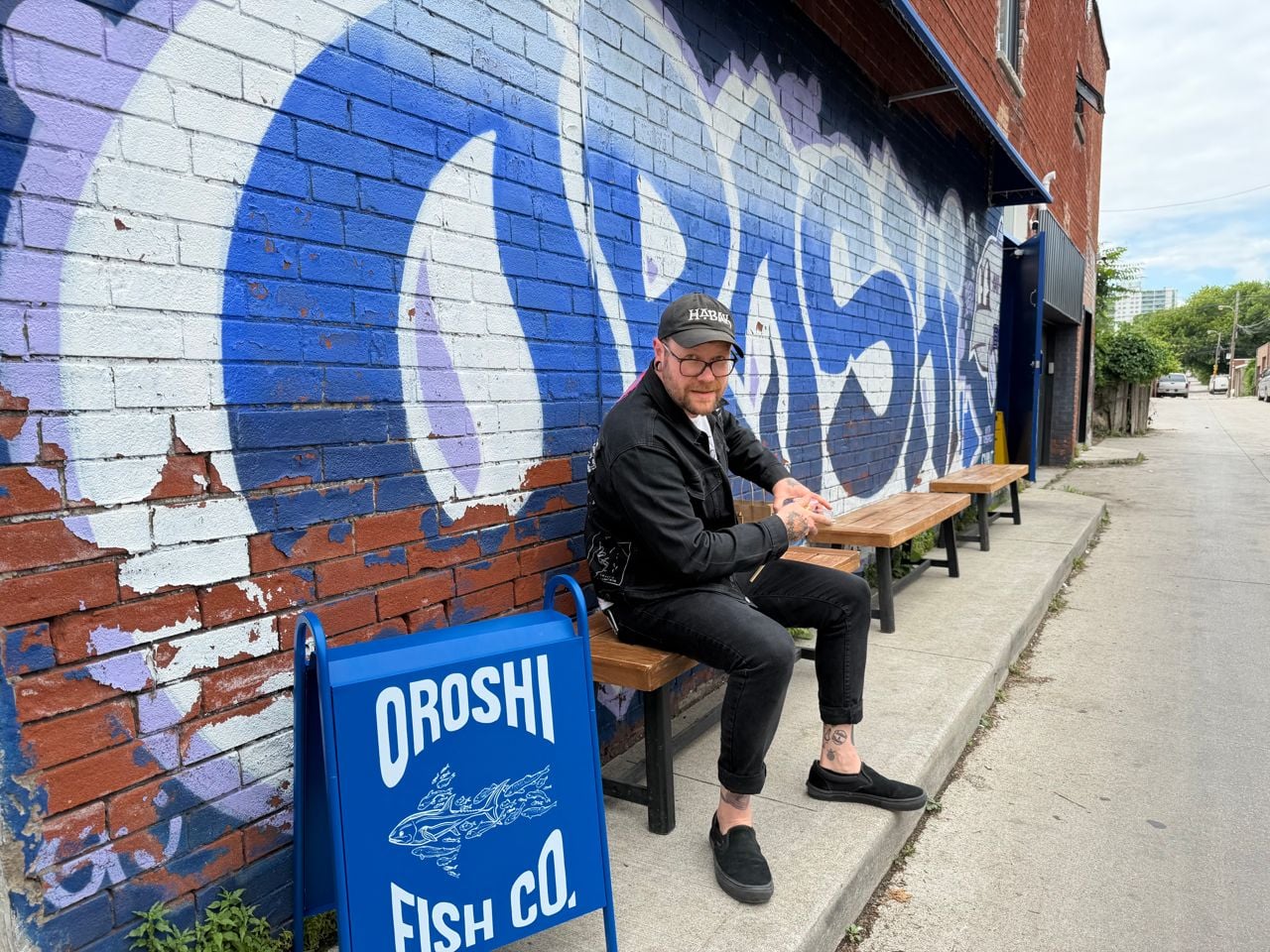 Chef Taylor McMeekin sits on a bench outside of Oroshi Fish Co.