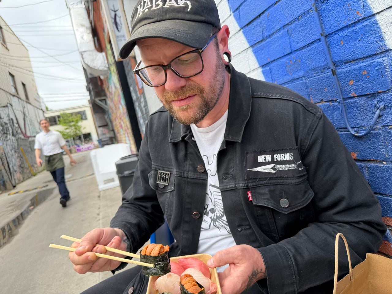 Chef Taylor McMeeking sits outside of Oroshi Fish Co. with an order of nigiri