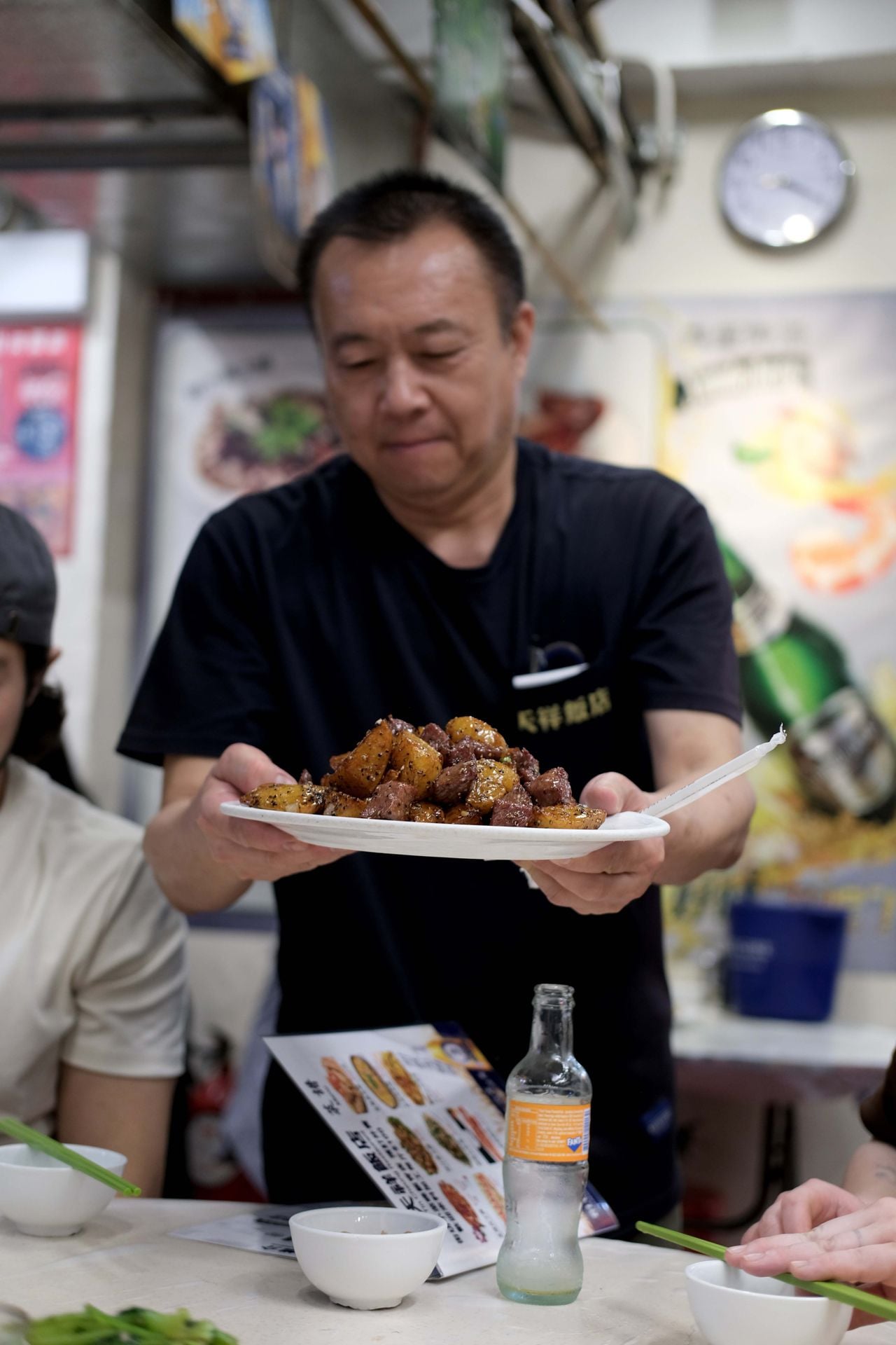A server at Tin Cheun carries a plate of beef and potatoes