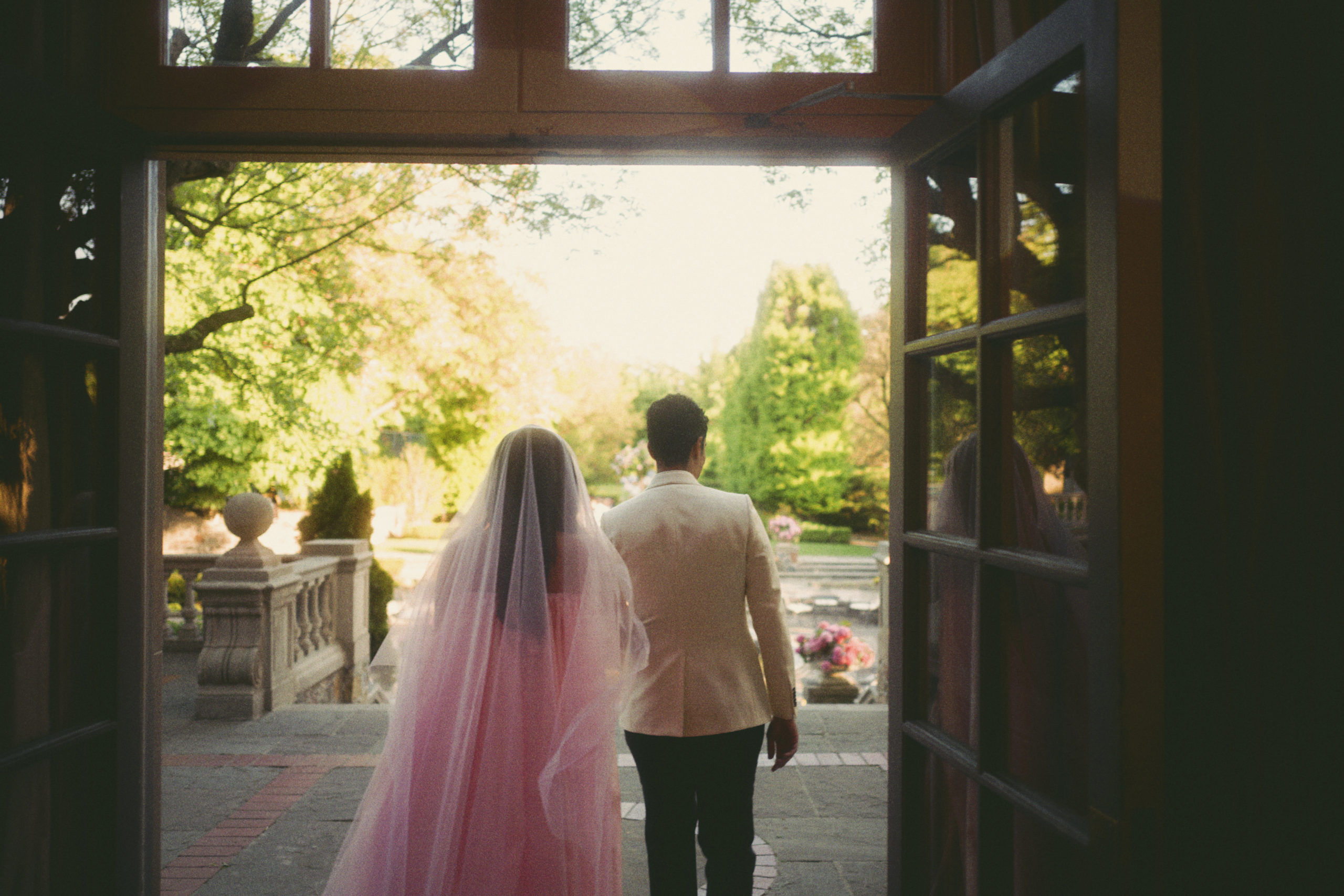 Roya and Mani walking through a doorway to outside, backlit