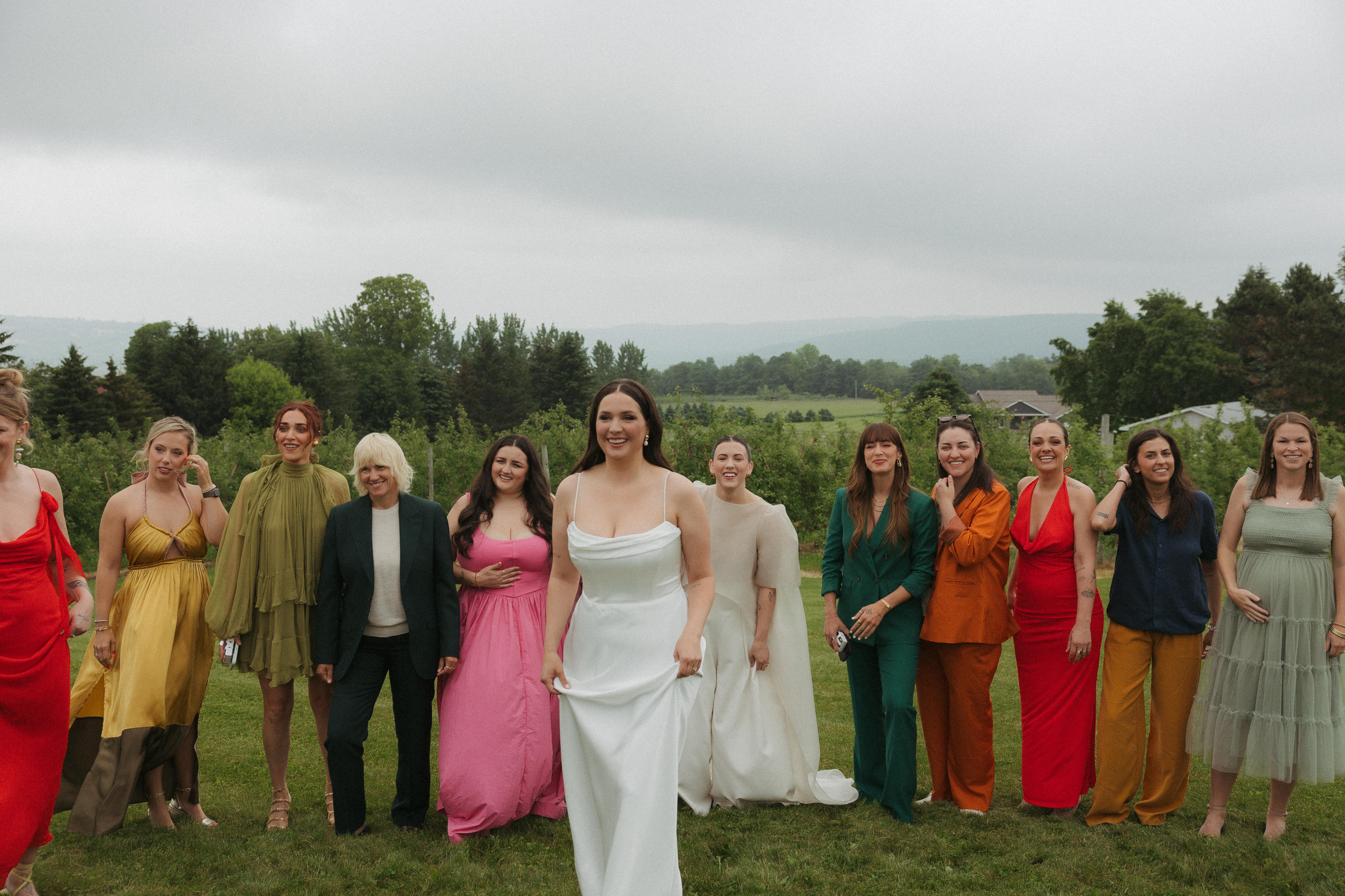 Two brides with colourful guests in the background.
