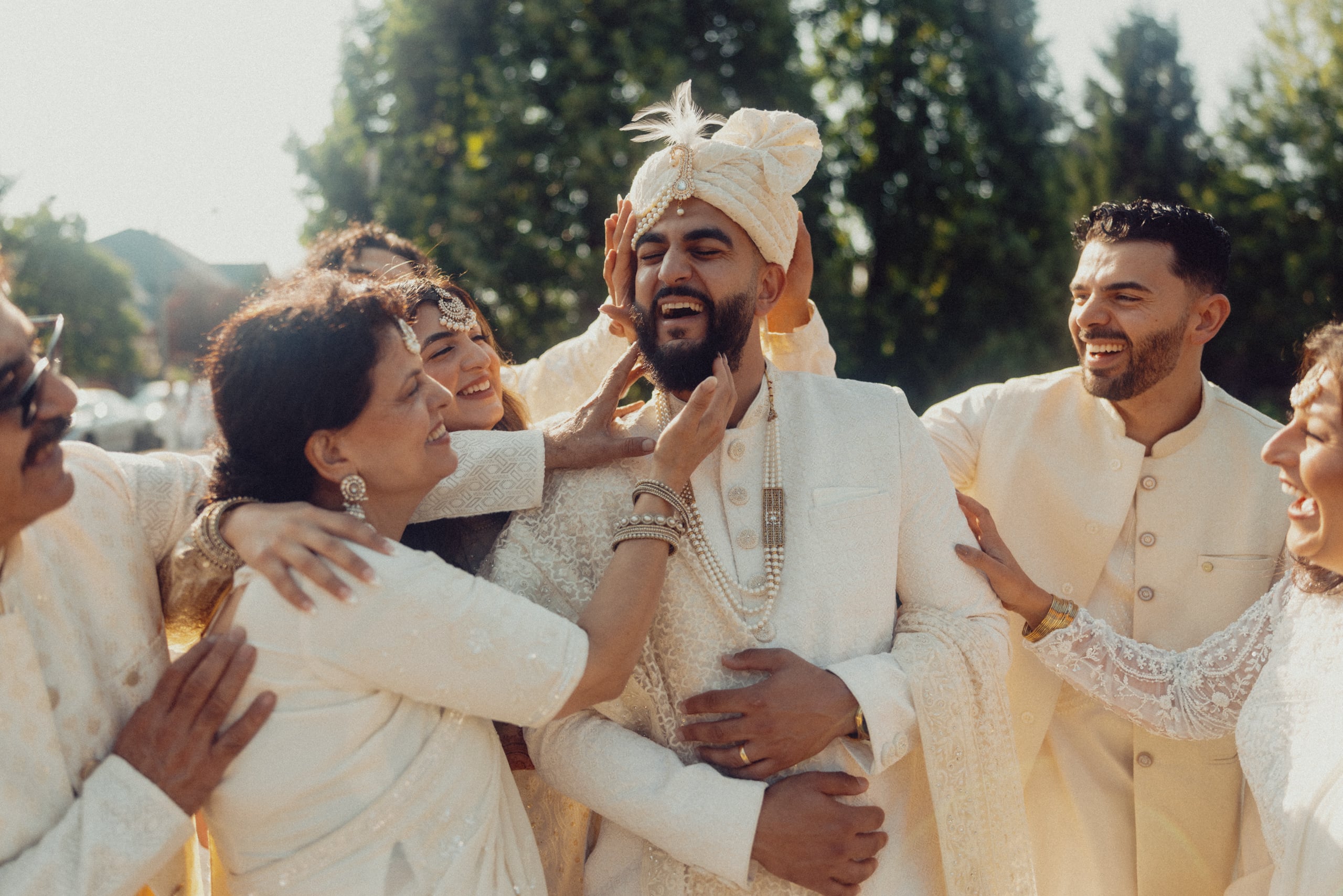Harris is embraced by several people while wearing a fully white outfit complete with white turban.