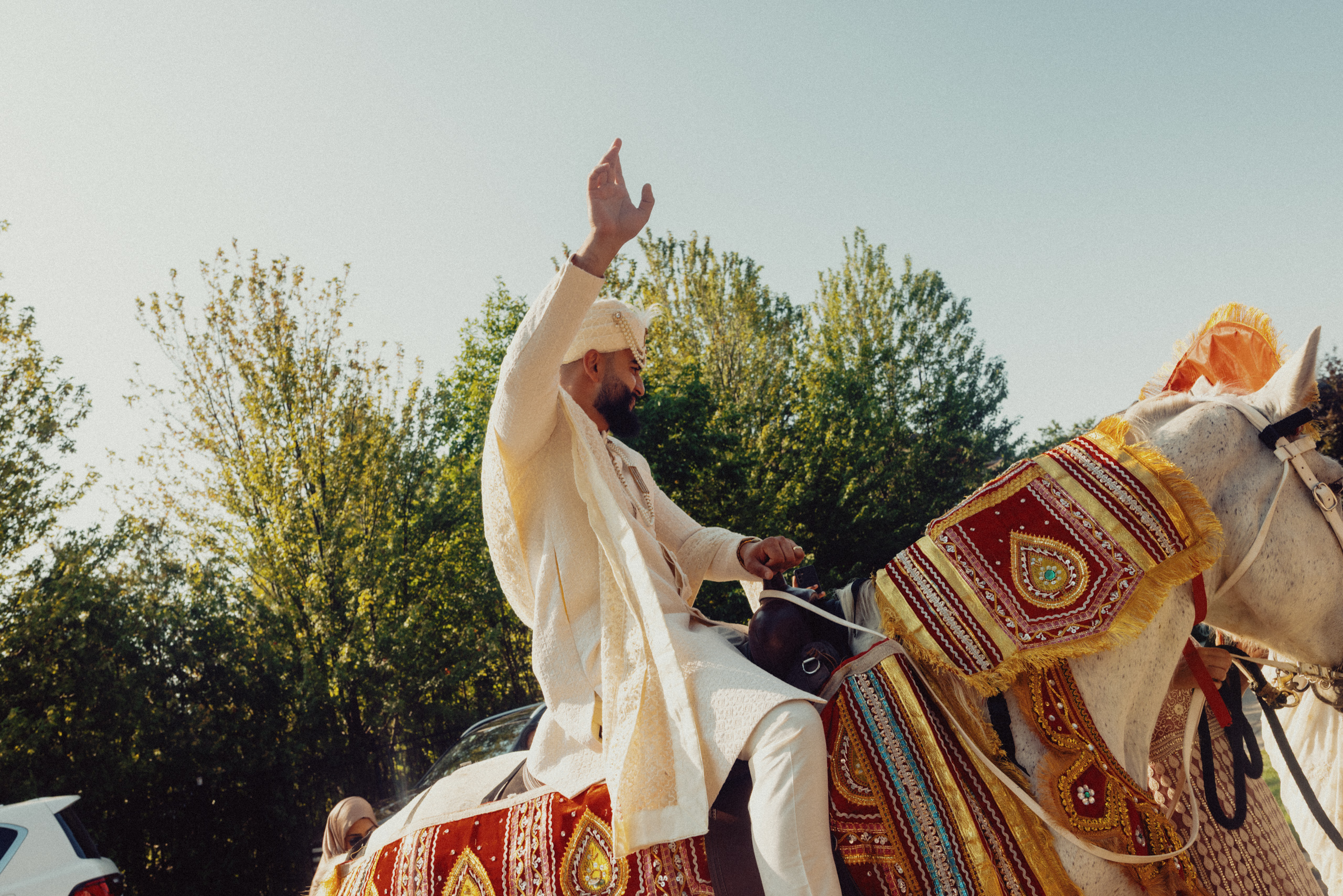 Harris waves with one hand while riding a horse.