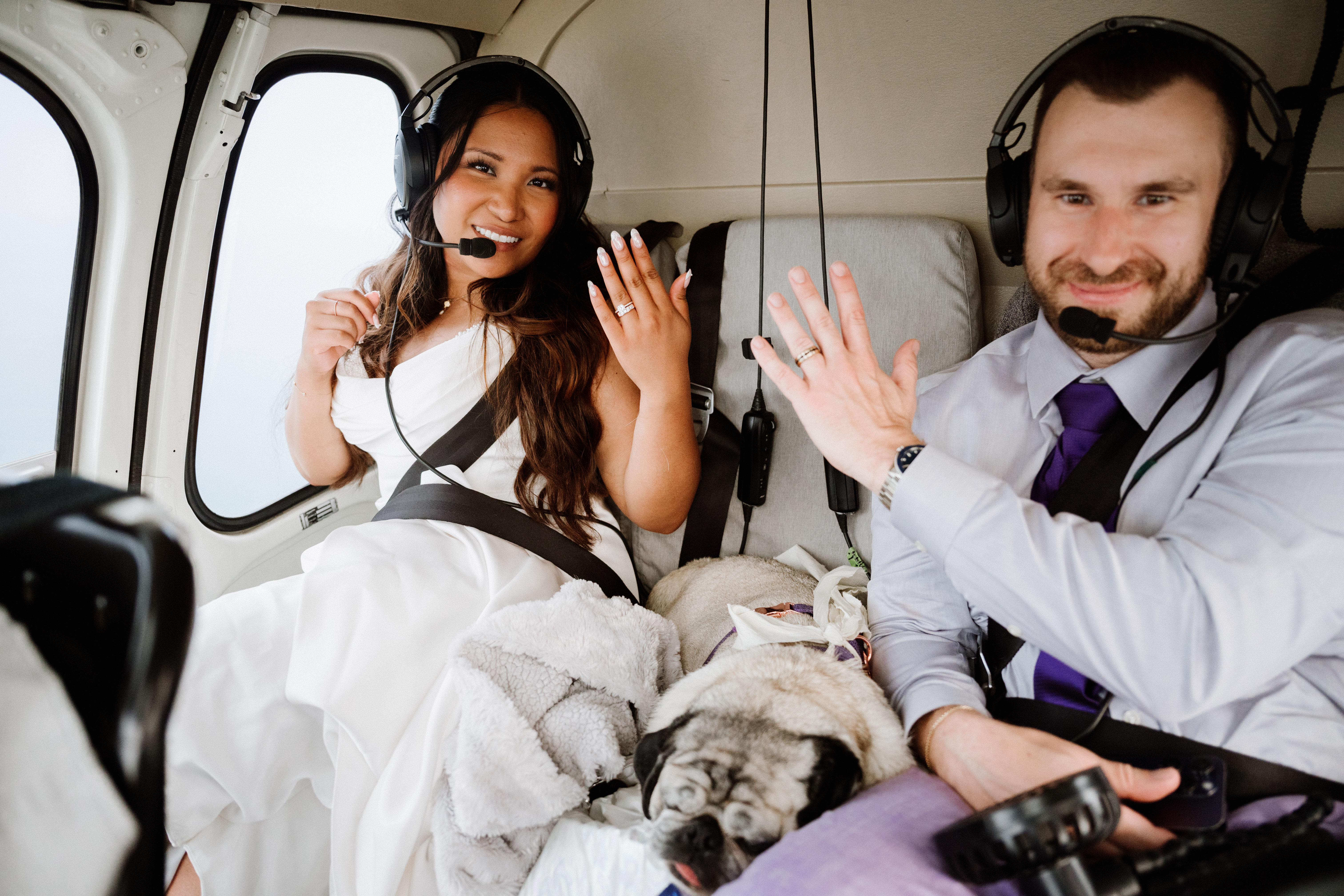 Bride and groom showing off rings in a helicopter