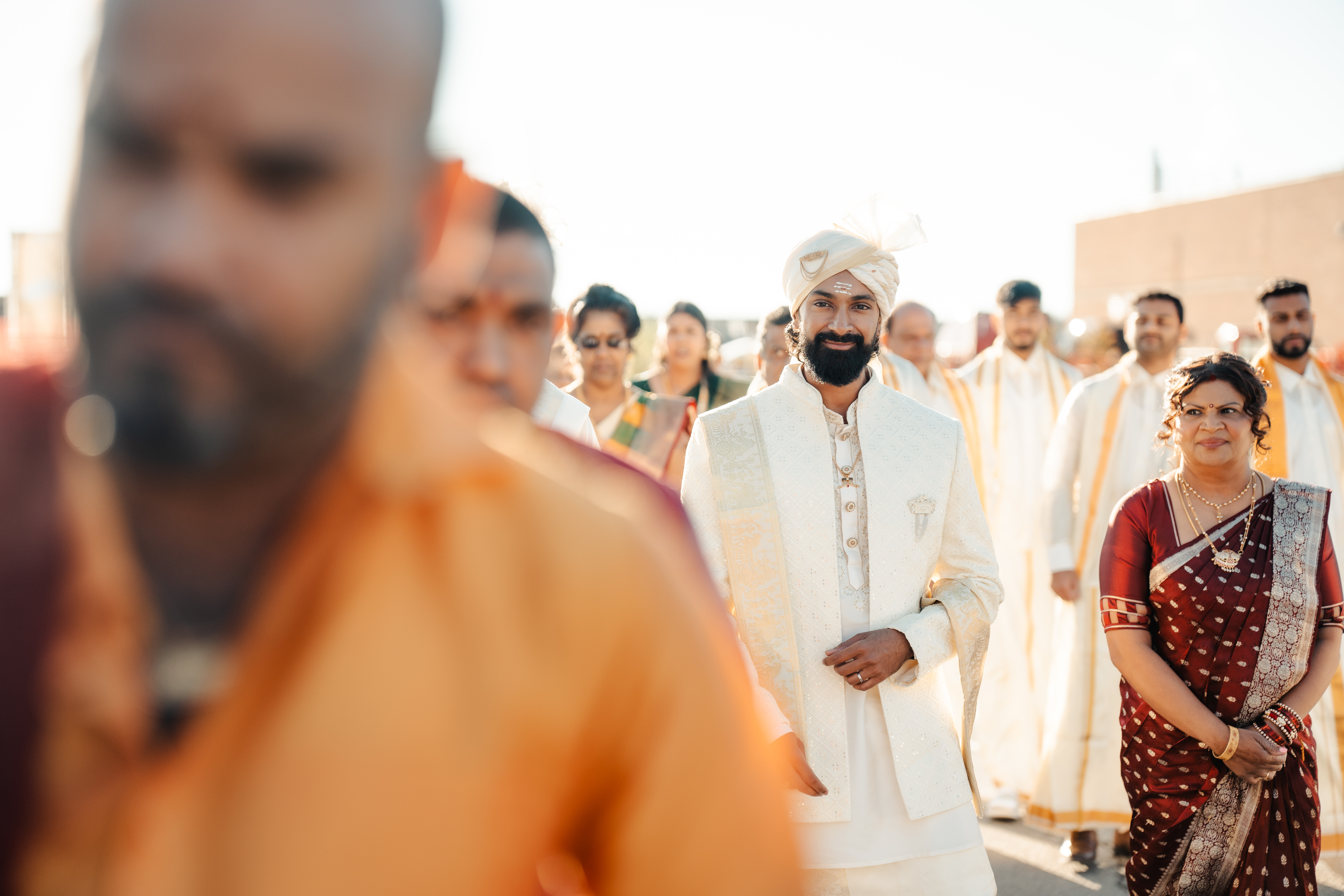 Groom wearing white in a wedding procession
