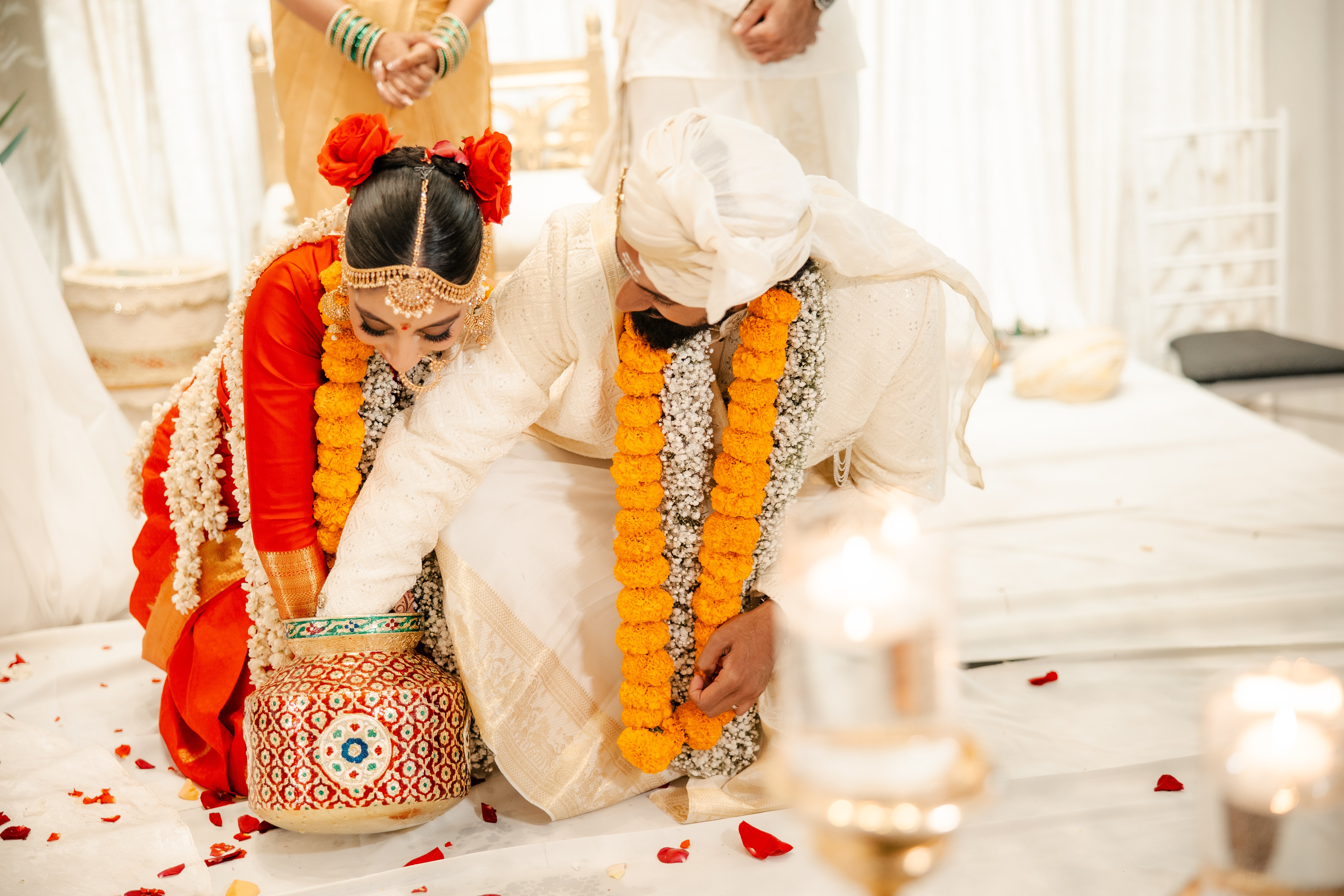 Bride and groom searching for ring in clay pot of milk