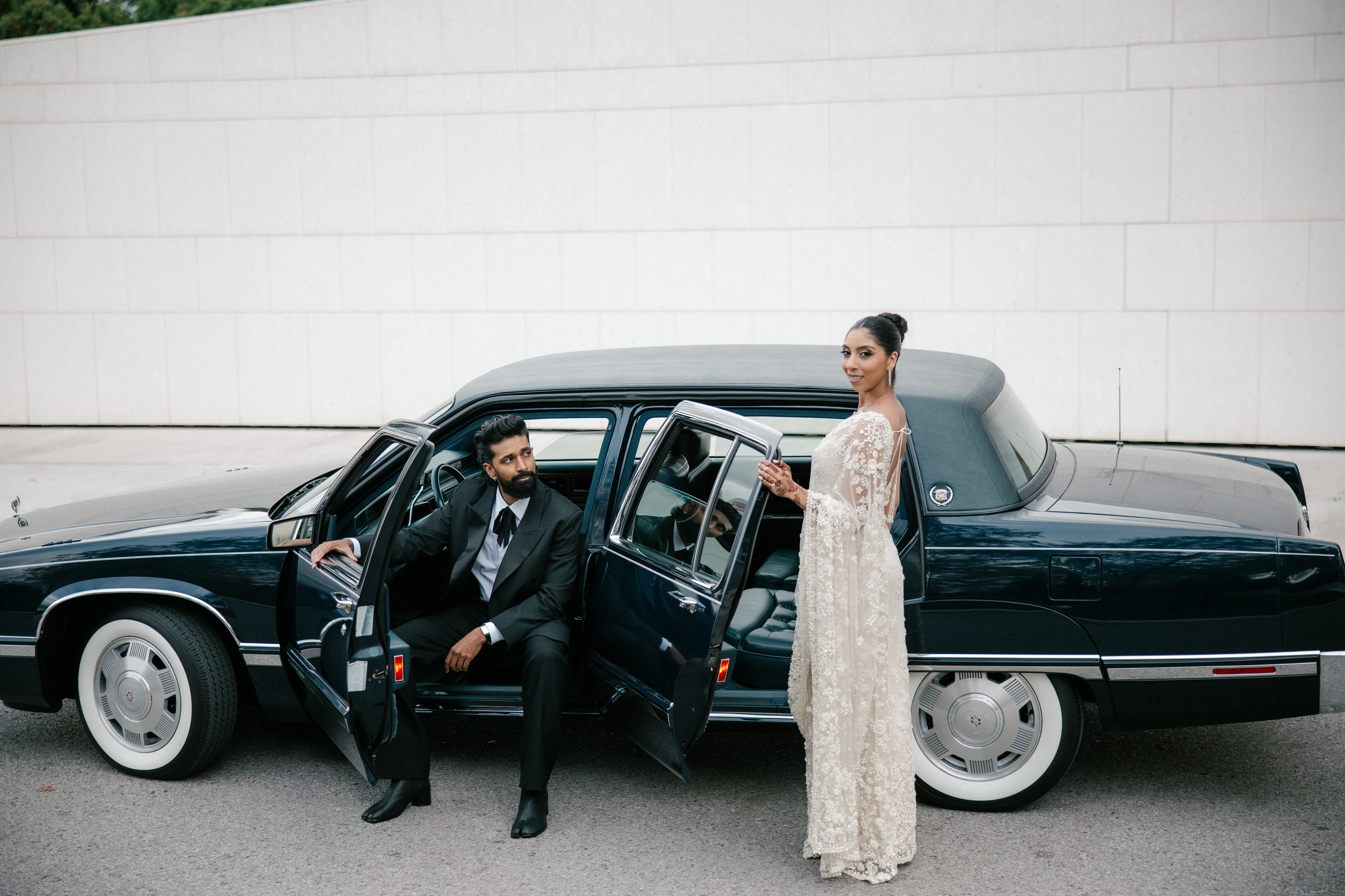 Elegant bride and groom getting into a black car